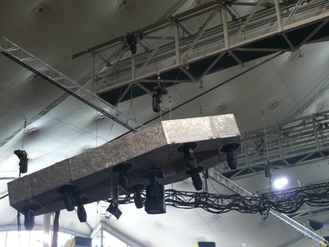 Metallica plays while surrounded by an audience huge speakers hang above the crowd