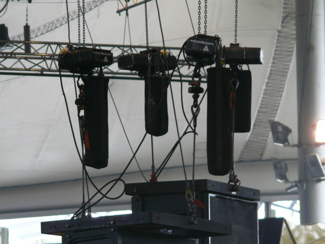 Metallica plays while surrounded by an audience huge speakers hang above the crowd