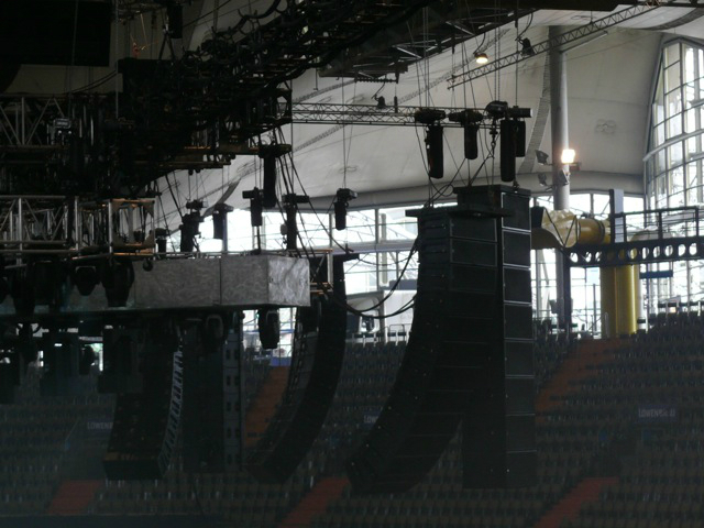 Metallica plays while surrounded by an audience huge speakers hang above the crowd