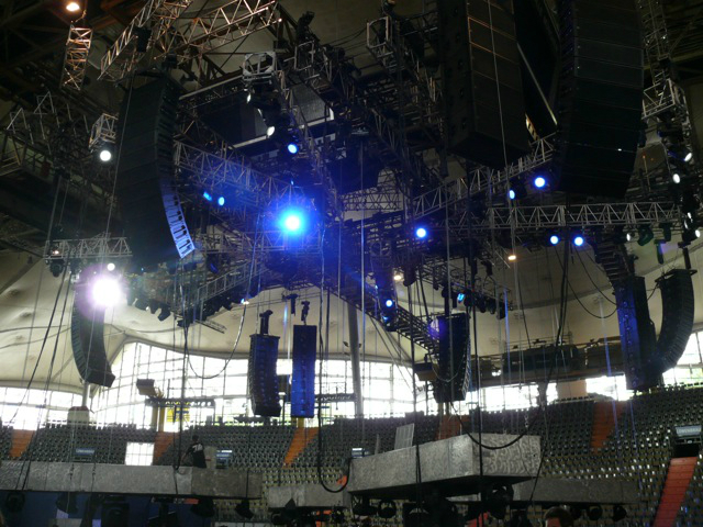 Metallica plays while surrounded by an audience huge speakers hang above the crowd